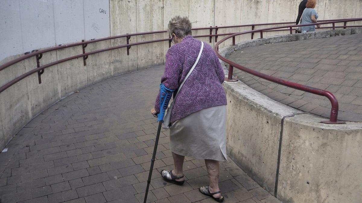 Una mujer con muletas sube por el paso subterráneo.