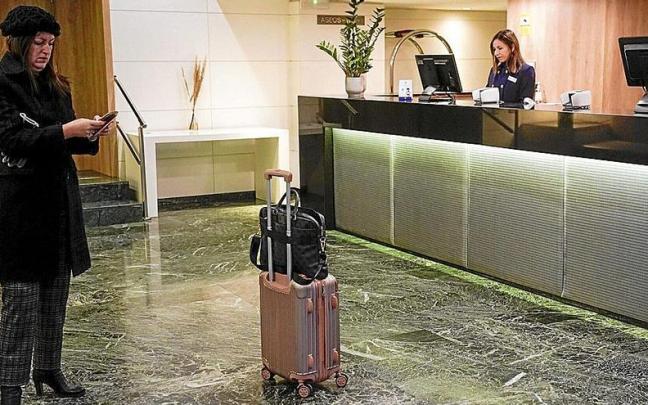 Una mujer espera a registrarse en el d&iacute;a de ayer en un hotel vitoriano. A la derecha, turistas a las puertas del establecimiento.