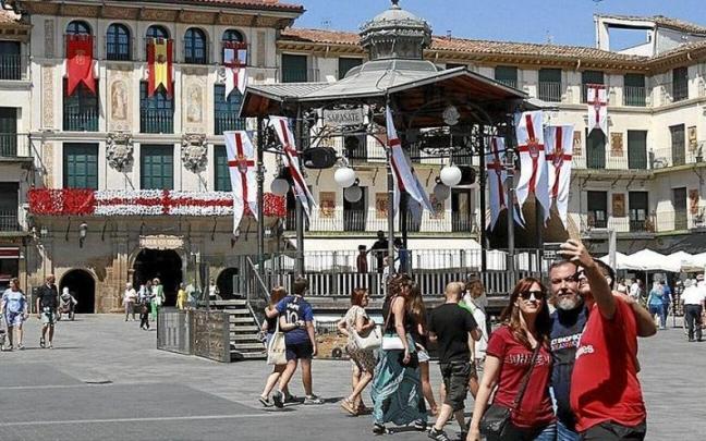 Tres amigos se hacen una fotografía, con el kiosco y la Casa del Reloj decorados, de fondo, donde hoy comenzarán las fiestas de Tudela.