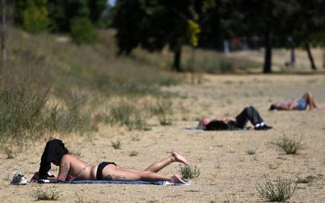 Varias personas toman el sol en un parque de Londres teñido de amarillo por la sequía. Varias personas toman el sol en un parque de Londres teñido de amarillo por la sequía.