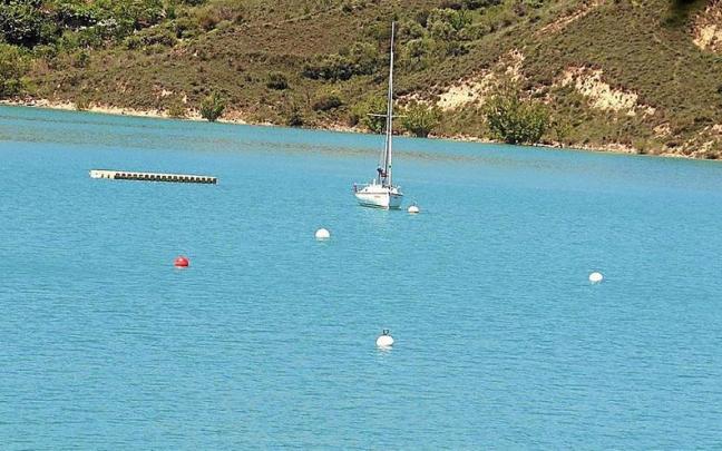 Un velero en el embalse, al fondo las orillas que serán objeto del proyecto Alloz Sostenible.