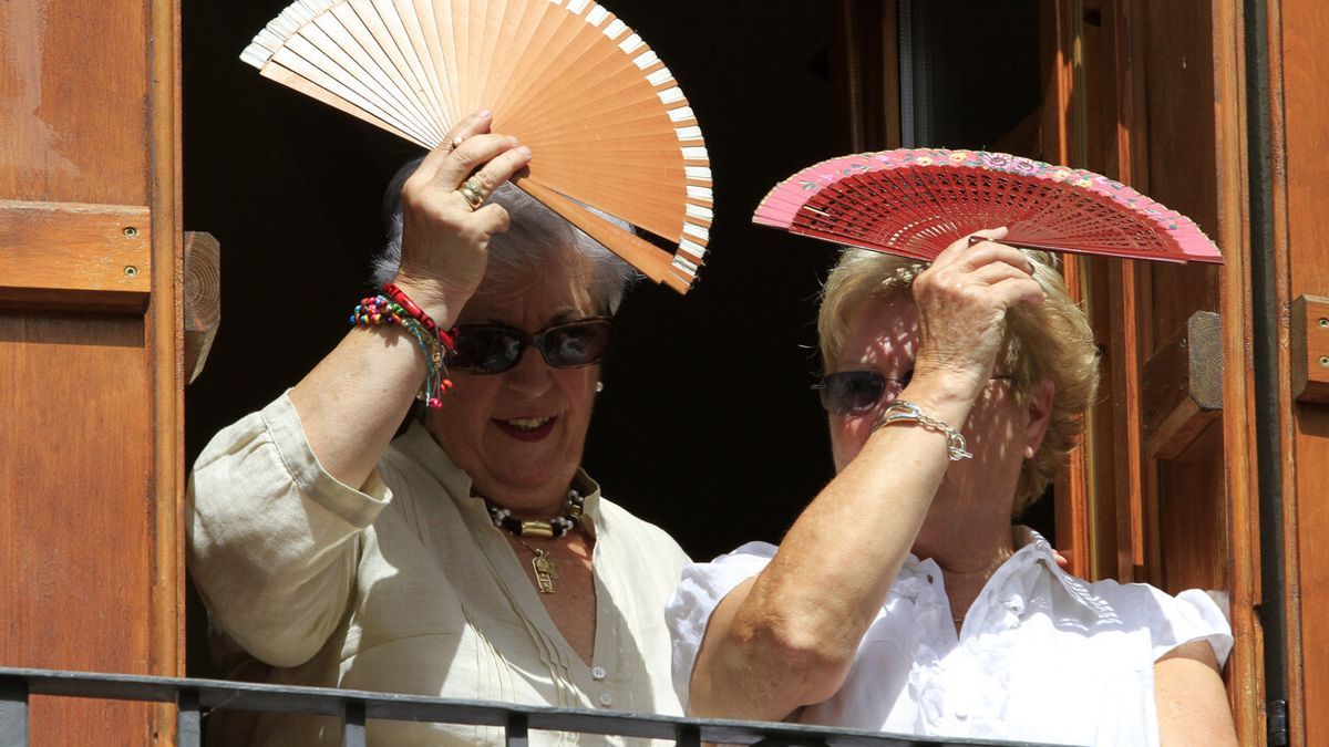 Dos mujeres se protegen del sol con dos abanicos en Aoiz