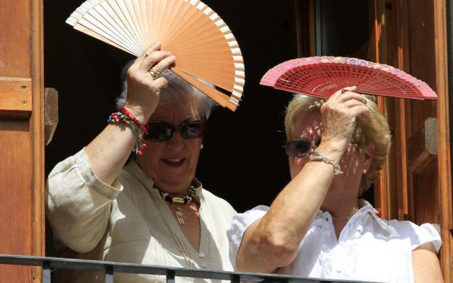 Dos mujeres se protegen del sol con dos abanicos en Aoiz