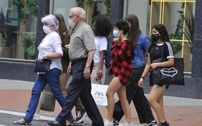 Varias personas pasean con mascarilla por la pandemia de coronavirus