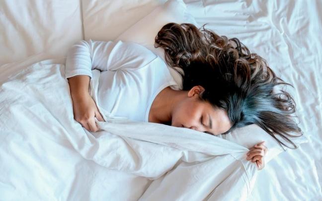 Una mujer se cubre parte del rostro con el edredón. Una mujer se cubre parte del rostro con el edredón.