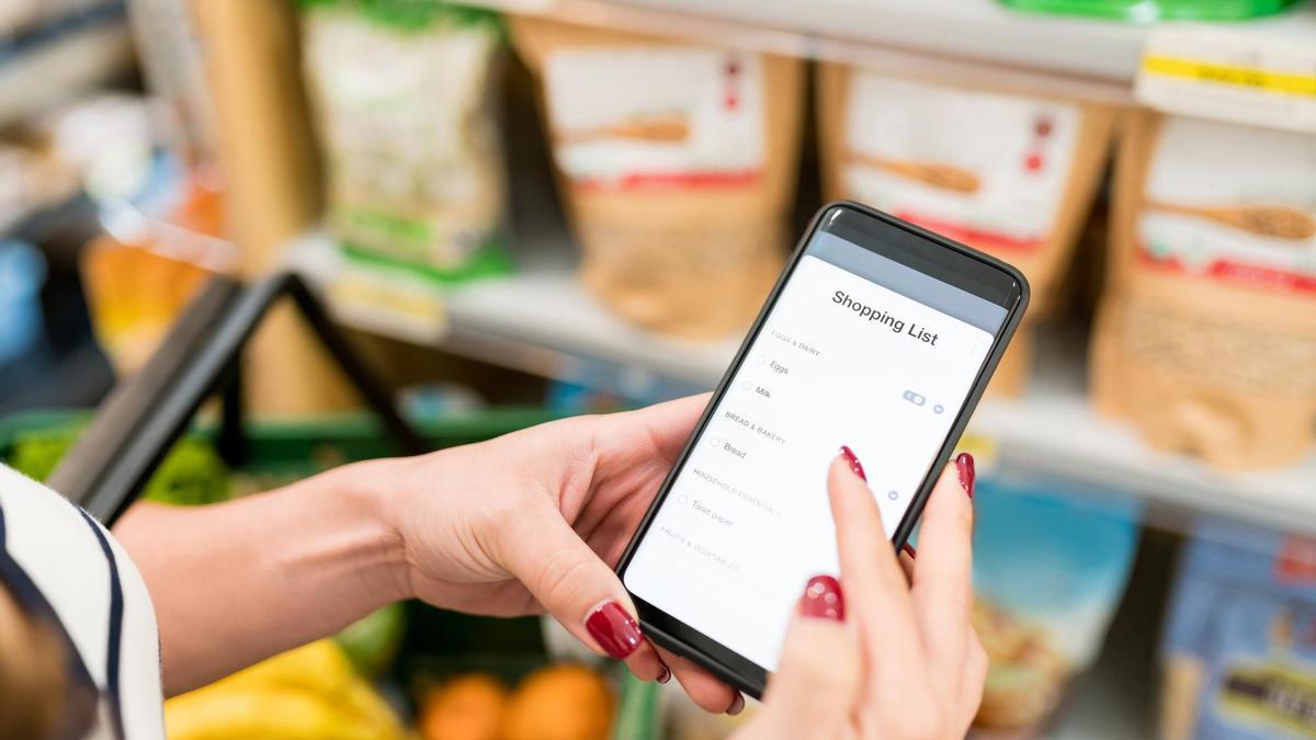 Una mujer utiliza una lista de compra digital en un supermercado.