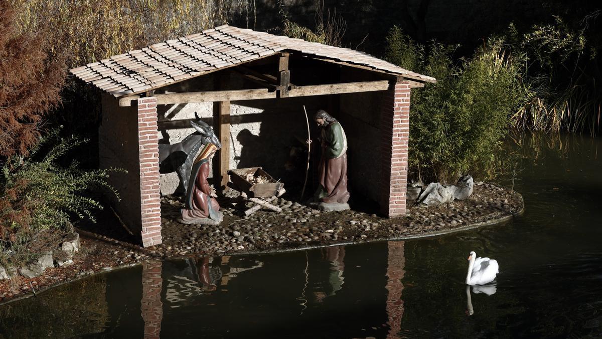 Un cisne pasa junto a un belén instalado en los fosos de La Taconera.