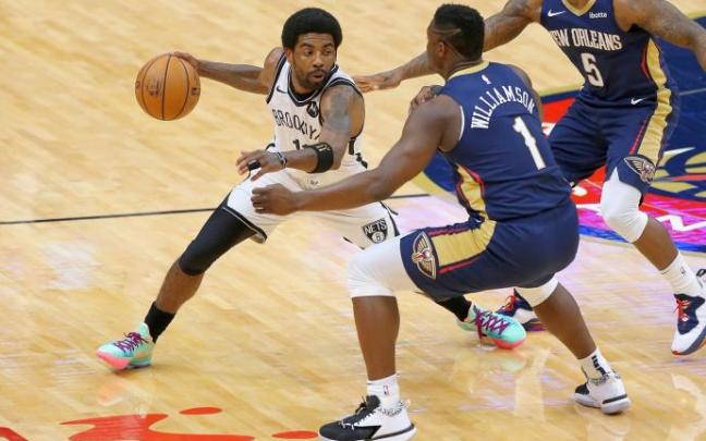 Kyrie Irving bota el balón ante la defensa de Zion Williamson.