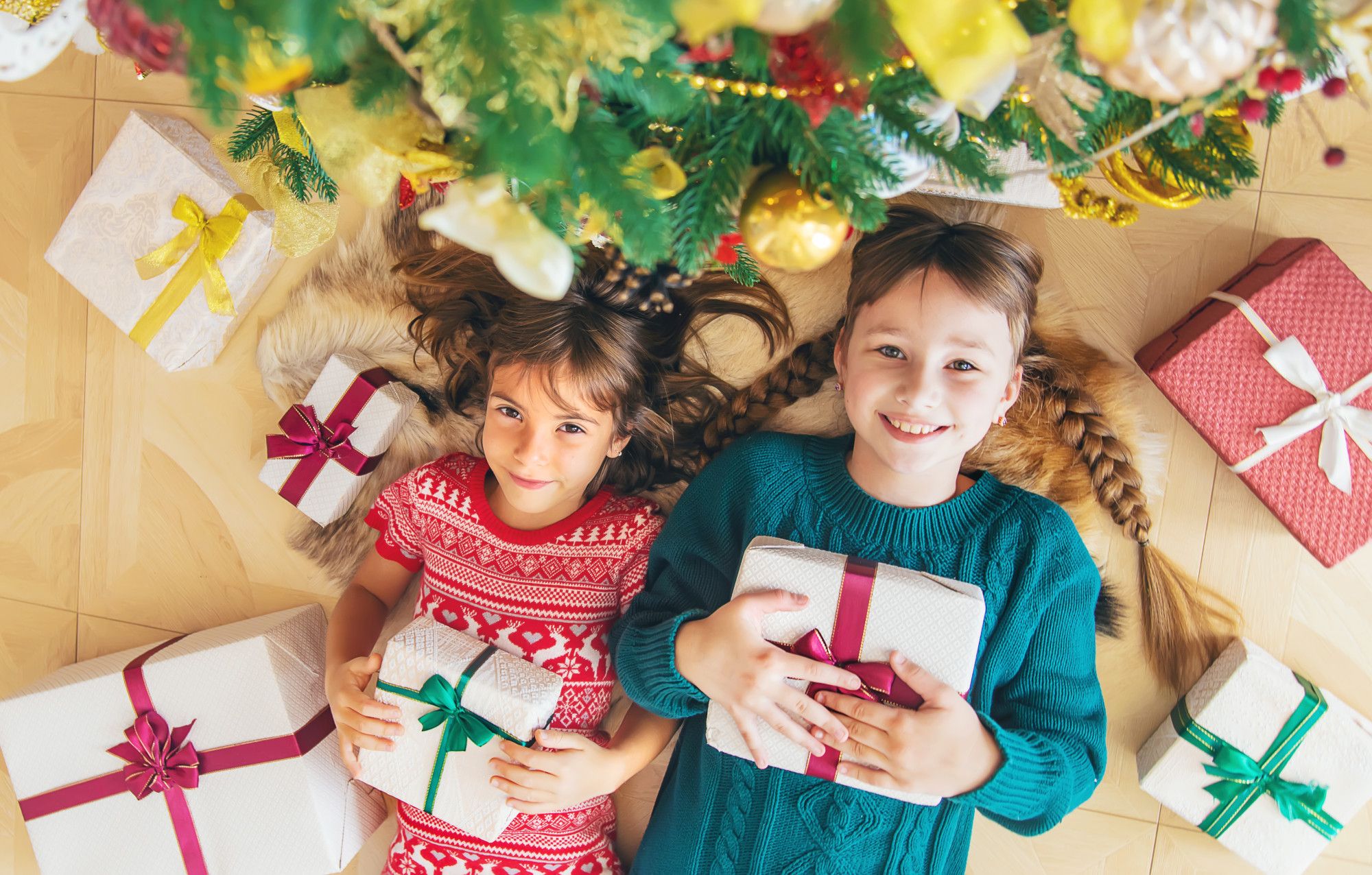 Dos niñas tumbadas rodeadas de regalos.