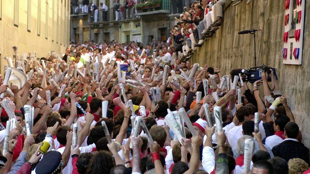 Cientos de mozos cantan a San Fermín en los momentos previos a un encierro.