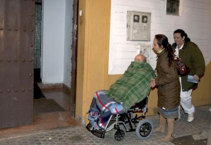 Una persona dependiente, atendida por dos mujeres en una residencia de ancianos.