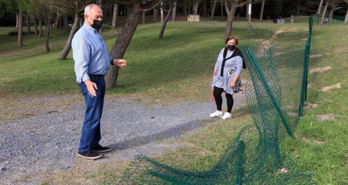 Paseantes observan los desperfectos en la valla del pinar de Gorliz.