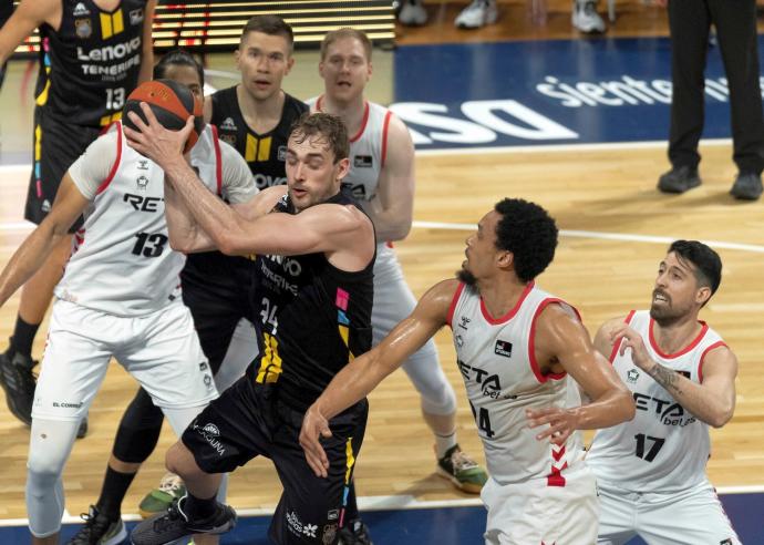 El jugador del Lenovo Tenerife Cavanaugh (c) y los jugadores del Bilbao Basket Dos Anjos (i), Jenkins (2d) y Athnaiou (d) durante el partido.