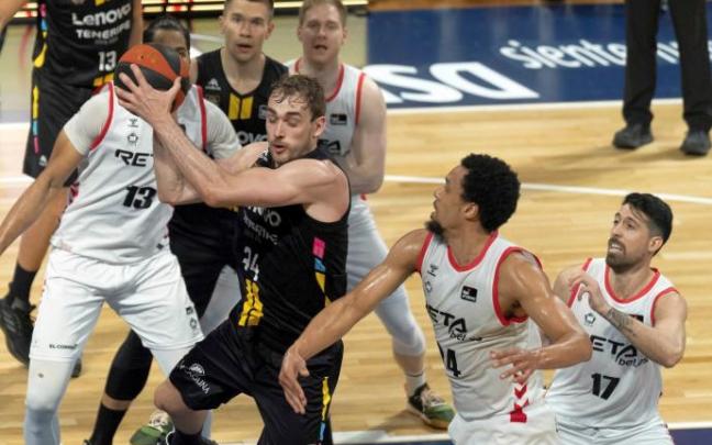 El jugador del Lenovo Tenerife Cavanaugh (c) y los jugadores del Bilbao Basket Dos Anjos (i), Jenkins (2d) y Athnaiou (d) durante el partido.