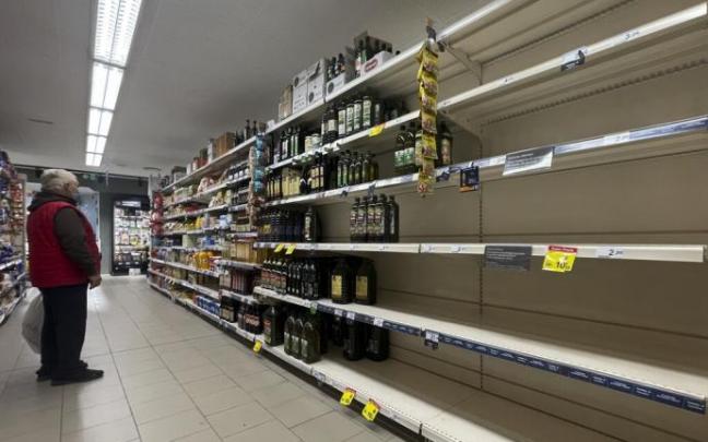 Un hombre contempla unas estanterías semivacías.