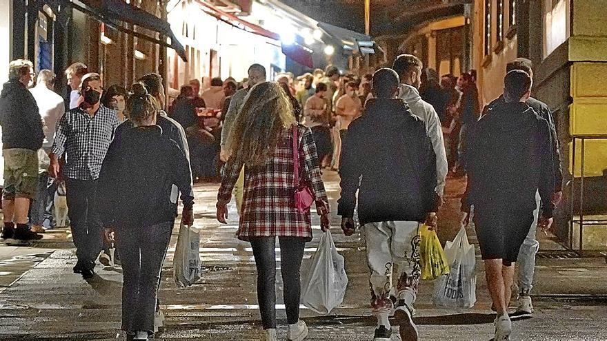 Varios jóvenes cargan con bolsas llenas de bebidas alcohólicas por la calle en una zona de bares. | FOTO: OSKAR M. BERNAL