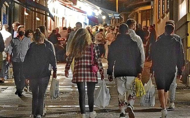 Varios j&oacute;venes cargan con bolsas llenas de bebidas alcoh&oacute;licas por la calle en una zona de bares. | FOTO: OSKAR M. BERNAL