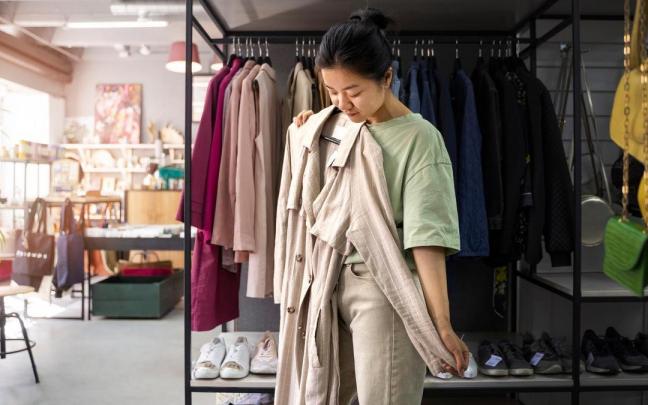 Una mujer sujeta una gabardina en una tienda de ropa.