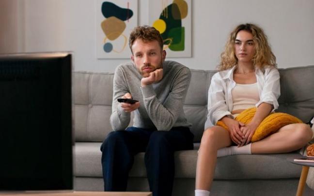 Pareja joven viendo la televisión tranquilamente en el sofá. Pareja joven viendo la televisión tranquilamente en el sofá.