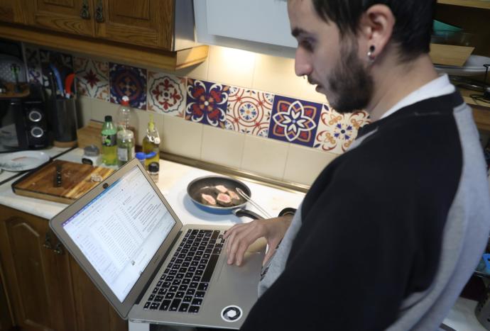 Una persona teletrabaja en la cocina de su domicilio.