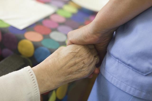 Una cuidadora da la mano a una paciente.