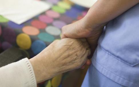 Una cuidadora da la mano a una paciente. Una cuidadora da la mano a una paciente.