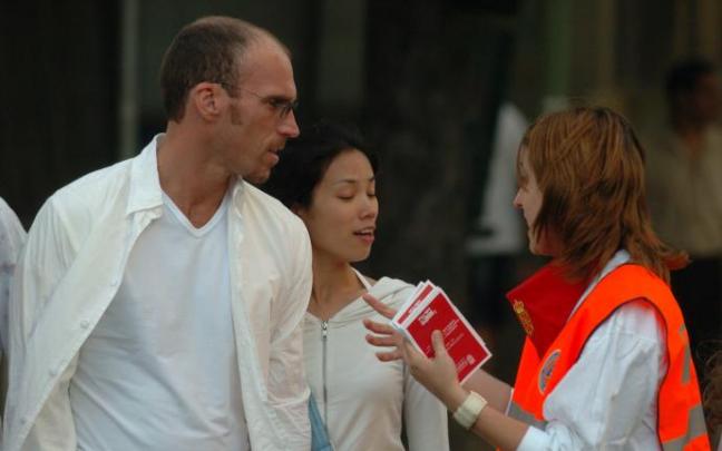Una joven trabajadora de Protección Civil (naranjito) ofreciendo información a una pareja. Una joven trabajadora de Protección Civil (naranjito) ofreciendo información a una pareja.