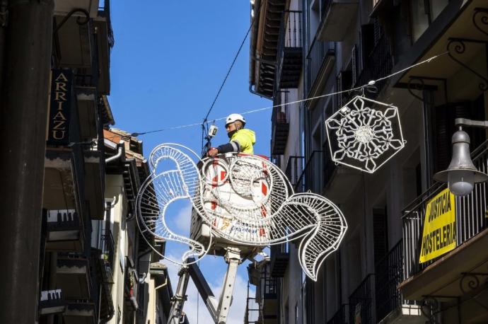 Un operario municipal coloca adornos navideños en la calle Pozo Blanco