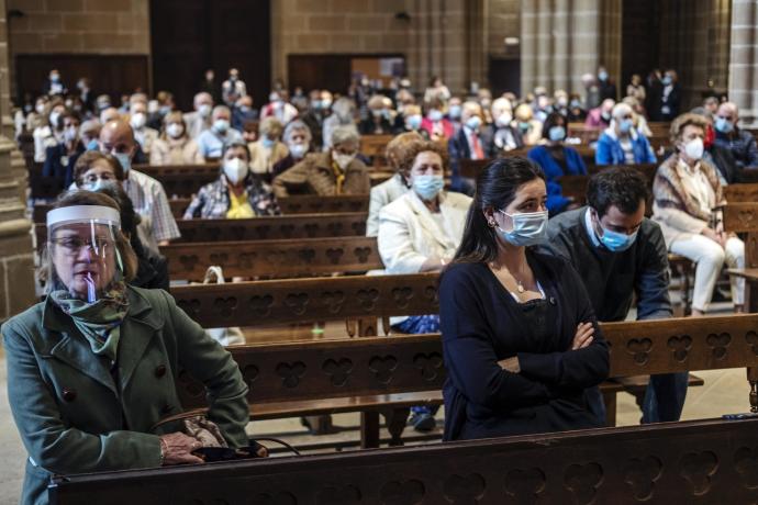 Fieles con mascarilla y manteniendo las distancias de seguridad por la crisis sanitaria del coronavirus, durante la misa del Día del Corpus Christi.