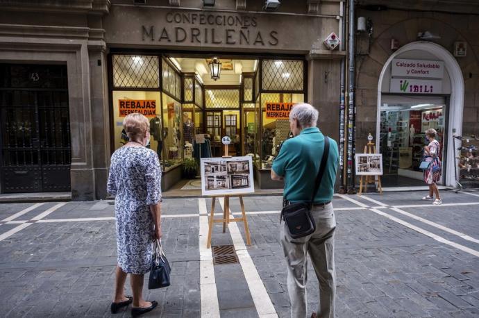 Una mujer y un hombre observan atentamente el panel histórico de Confecciones Madrileñas.