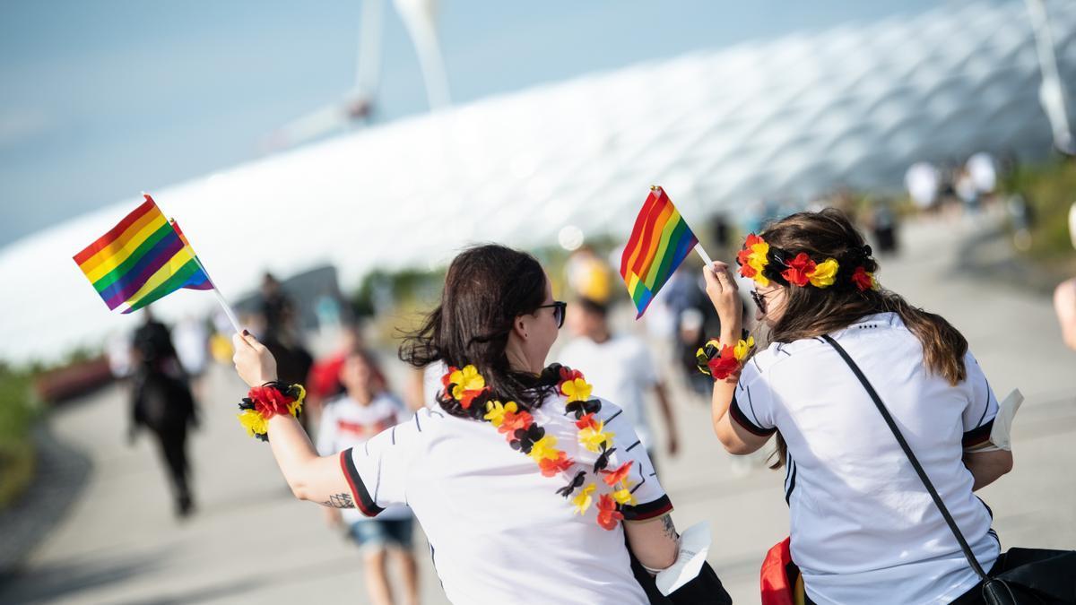 Aficionadas alemanas portan banderas con el arcoíris en favor de la comunidad LTGBIQ+.