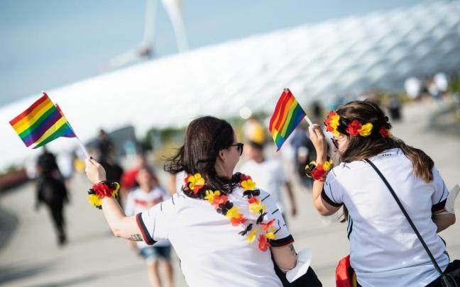 Aficionadas alemanas portan banderas con el arcoíris en favor de la comunidad LTGBIQ+.