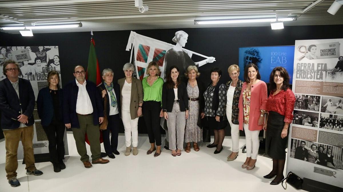 Las tres comisarias de la exposición 'EAB 100 urte. Emakumeak Aberria eginez', junto a parte de los y las representantes institucionales que han acudido a la inauguración