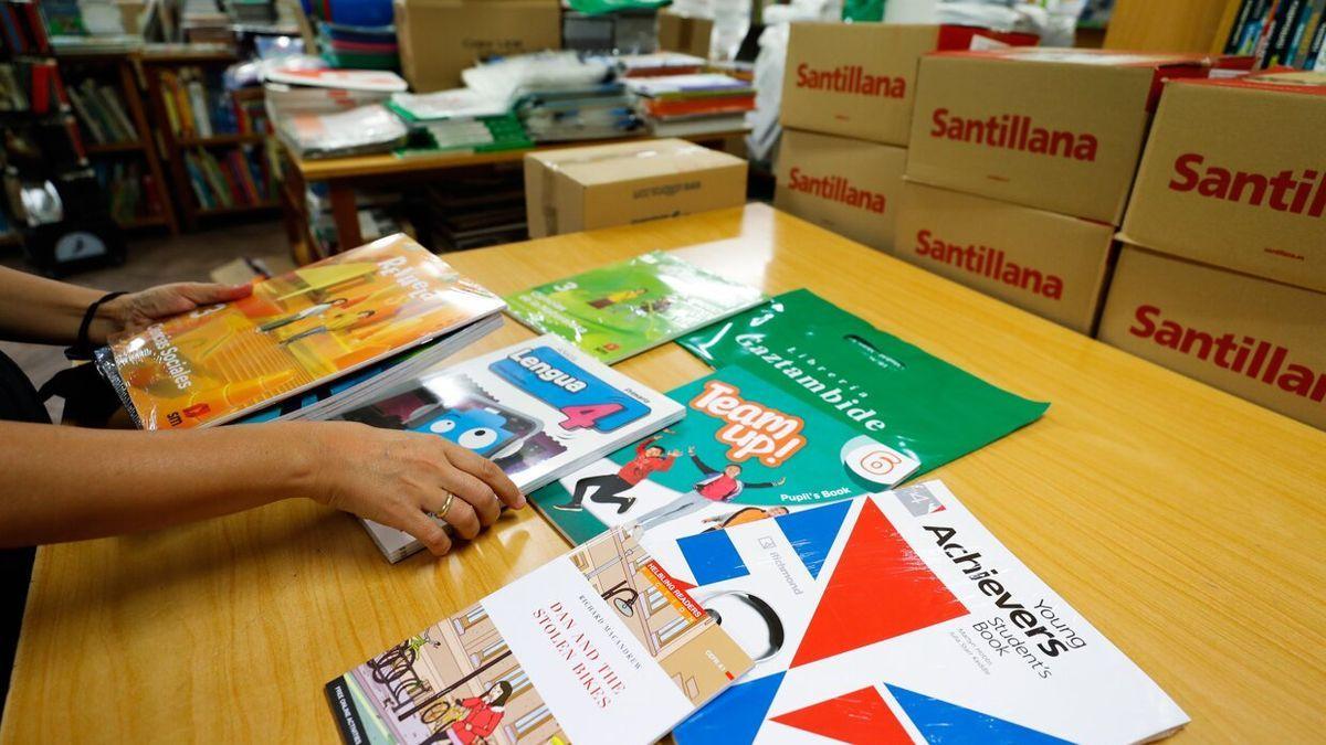 Una mujer sostiene varios libros de texto en una librer&iacute;a.