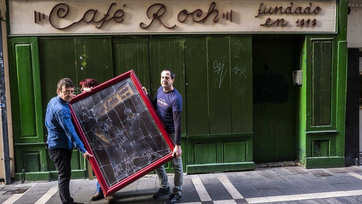 Dos empleados del Café Roch trasladan un cuadro del local, tras recoger las últimas pertenencias antes de que se ejecutara el desahucio.