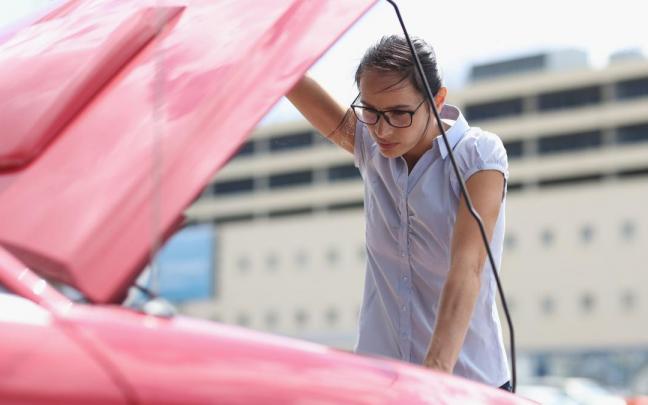 Una conductora revisa el motor de su coche.