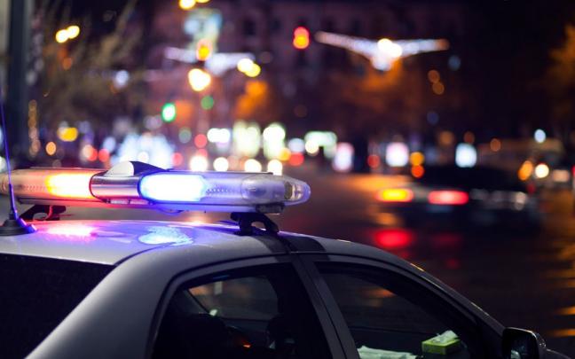 Un coche de la polic&iacute;a patrulla la ciudad por la noche.