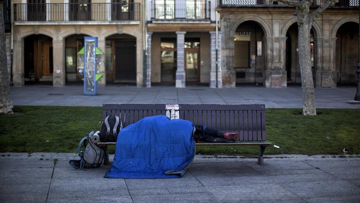 Una persona sin hogar durmiendo en un banco de la plaza del Castillo durante la pandemia del coronavirus.