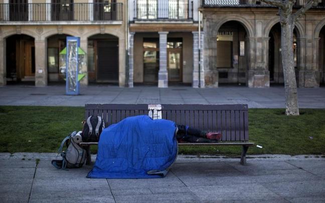 Una persona sin hogar durmiendo en un banco de la plaza del Castillo durante la pandemia del coronavirus.