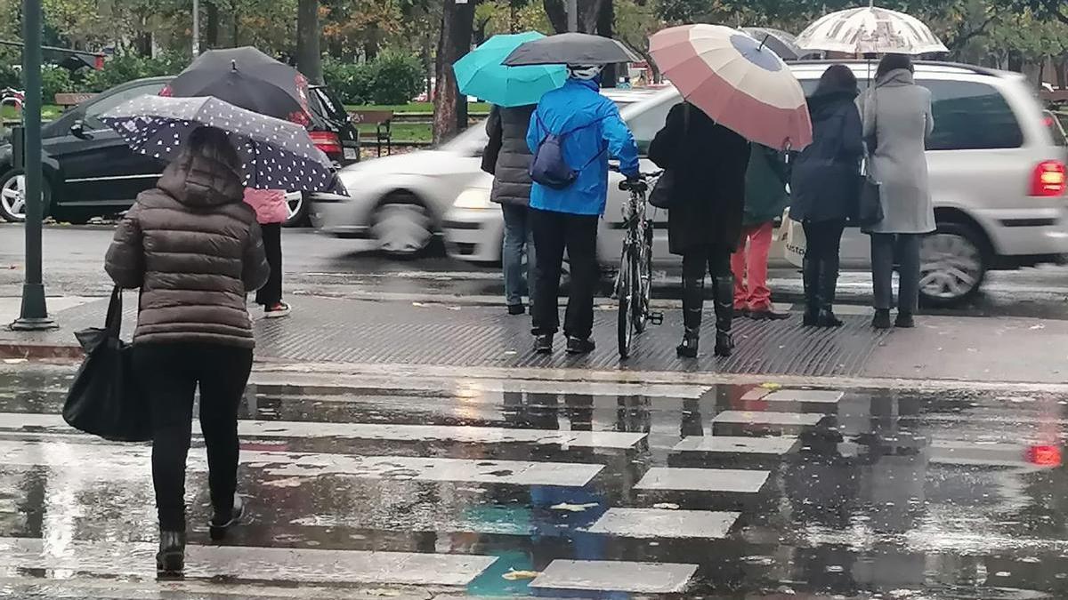 Vitorianos cruzando un semáforo bajo la lluvia este lunes en la Avenida Gasteiz