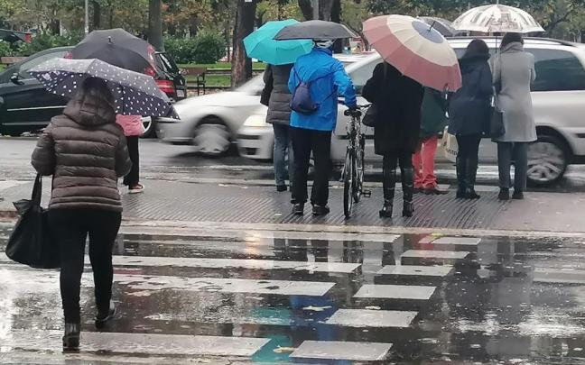 Vitorianos cruzando un semáforo bajo la lluvia este lunes en la Avenida Gasteiz
