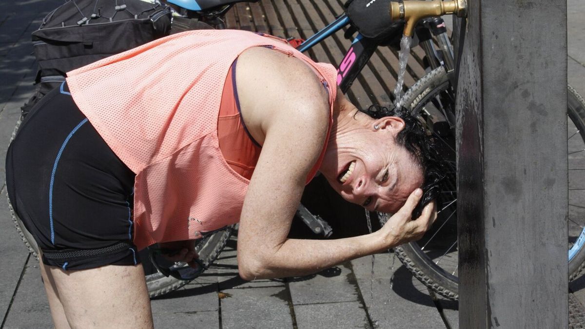 Una mujer refrescándose en una fuente durante la pasada ola de calor.