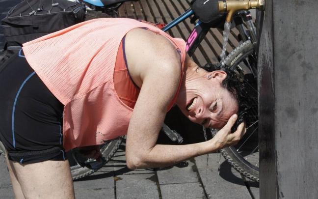 Una mujer refrescándose en una fuente durante la pasada ola de calor.