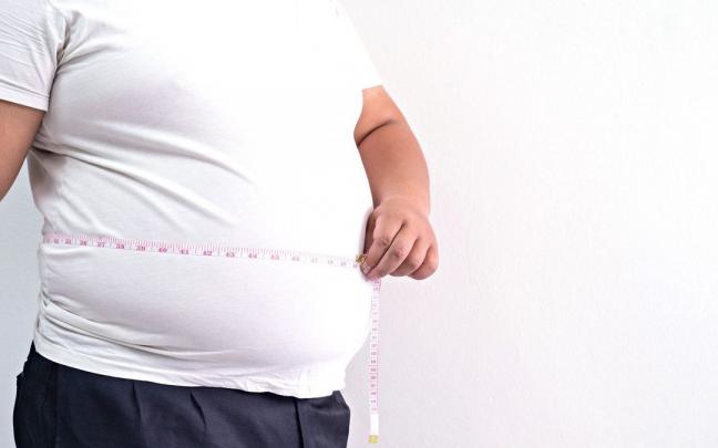 Un hombre obeso mide su cintura con una cinta métrica. Un hombre obeso mide su cintura con una cinta métrica.