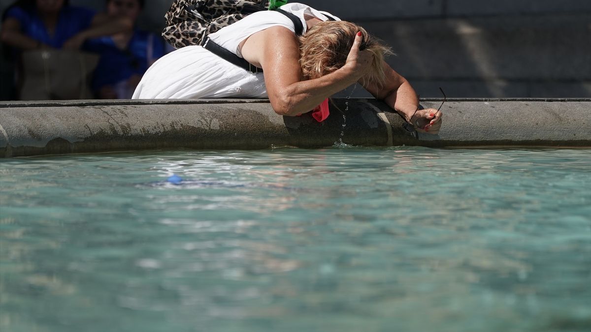 Una mujer se refresca en una fuente para combatir el calor