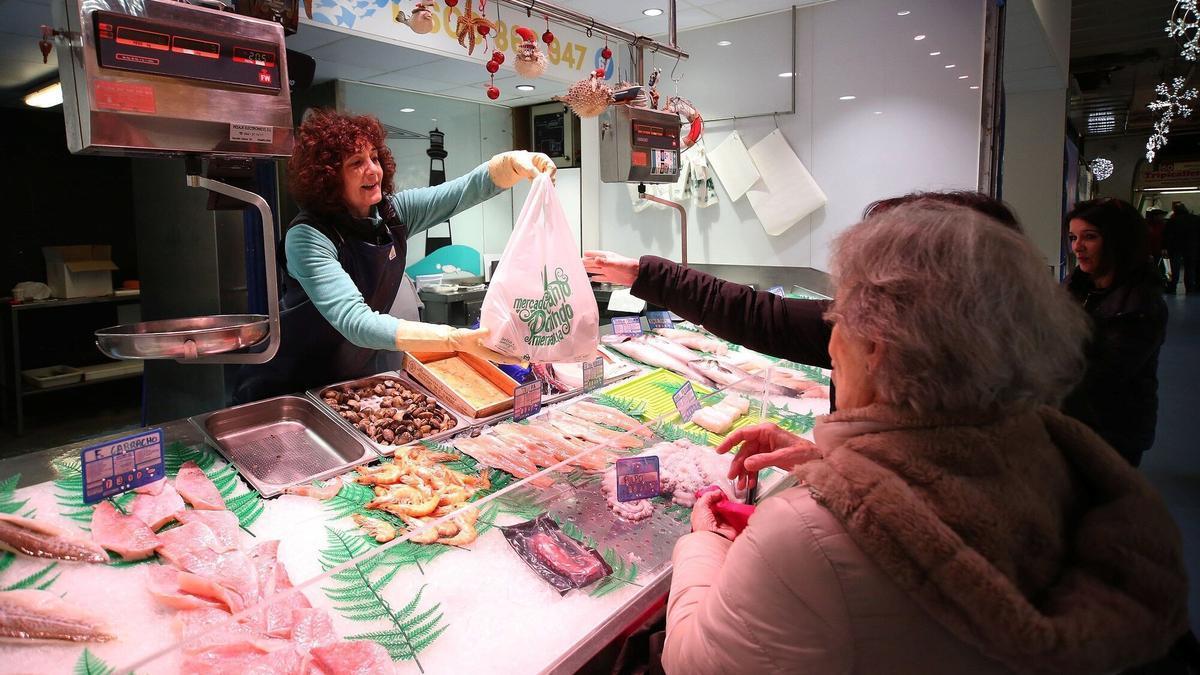 Raquel Viguria atiende a una clienta en su establecimiento en el mercado de Santo Domingo.