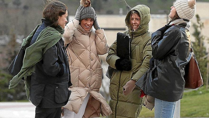 Cuatro jóvenes se protegen del viento, ayer en Pamplona. | FOTO: JAVIER BERGASA