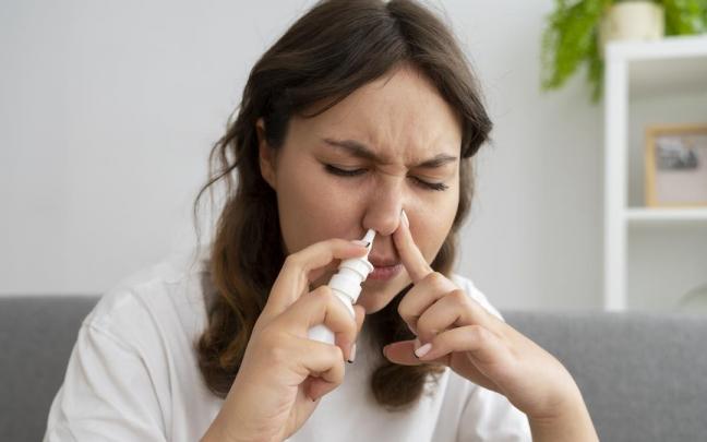 Una mujer hace uso de un spray nasal. Una mujer hace uso de un spray nasal.