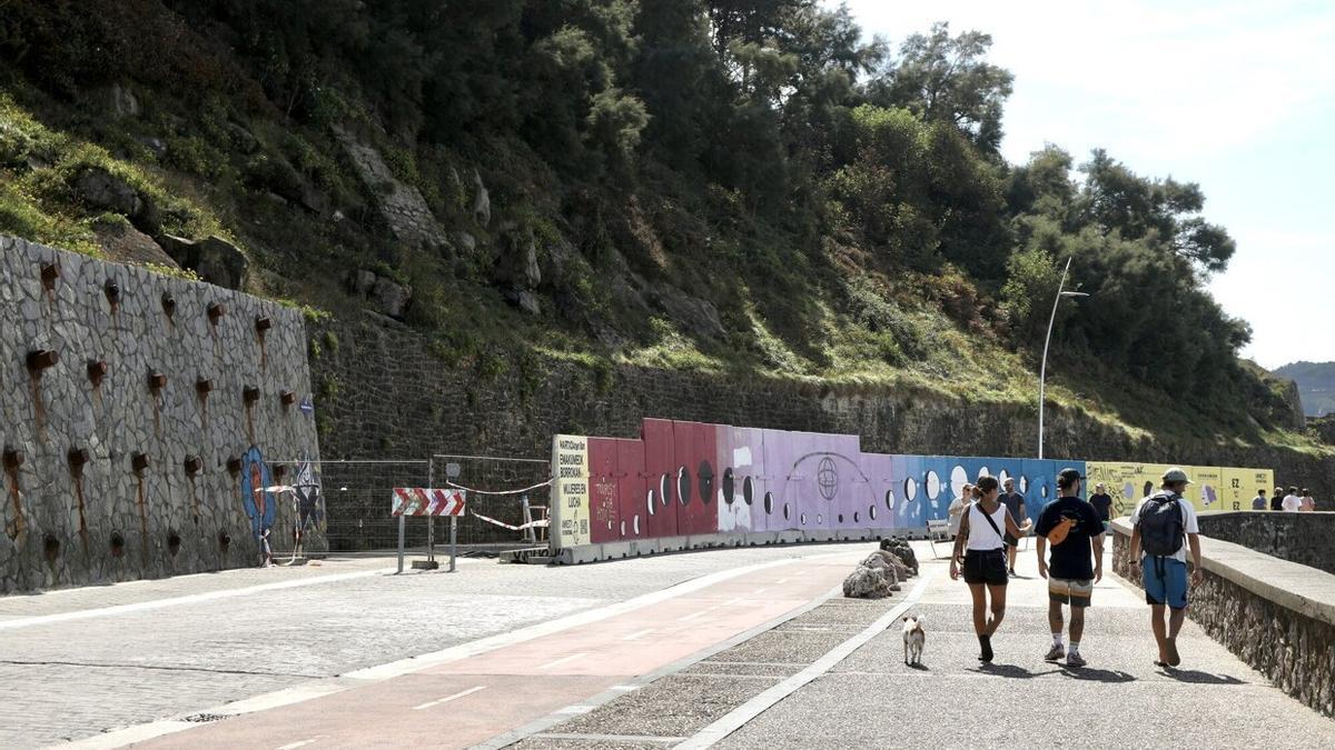 Personas pasan junto al muro afianzado y el de protección, que será retirado tras las obras.