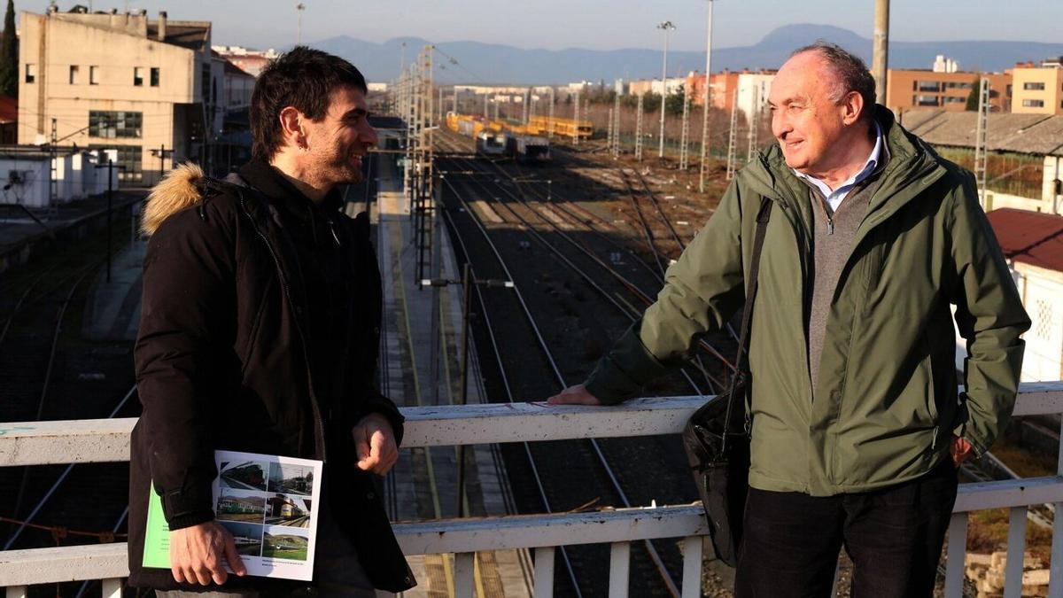 Mikel Santamaría y Juan Carlos Valerio, con la estación de Pamplona-Iruña de fondo, dialogan sobre la estrategia ferroviaria más idónea para Navarra.